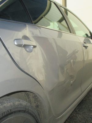 A car damaged from an auto accident before being repaired by Ding Pro.
