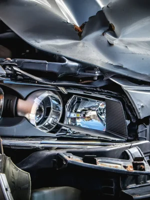 Front-end collision damage with crumpled hood and exposed headlight components